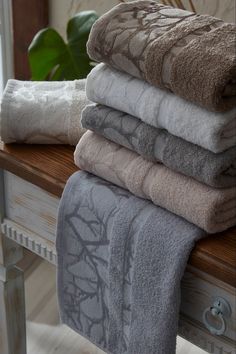 towels stacked on top of each other on a wooden table next to a potted plant