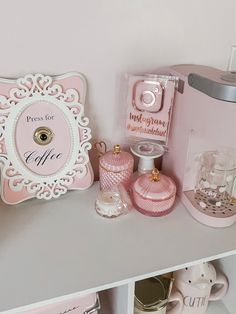 there is a shelf with pink and white items on it, including perfume bottles and other accessories