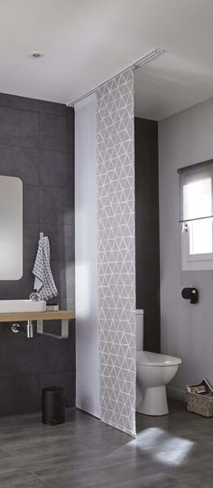 a bathroom with a toilet, sink and mirror in it's corner area next to a tiled wall