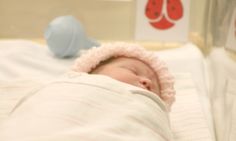 a baby is sleeping in a crib with a pink hat on