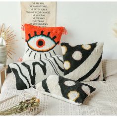 three decorative pillows on a bed next to a wall with an eye pillow and a sign