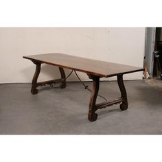 a wooden table sitting on top of a cement floor next to a white wall and door