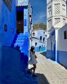 a woman in a white dress and hat is standing on the side of a blue building