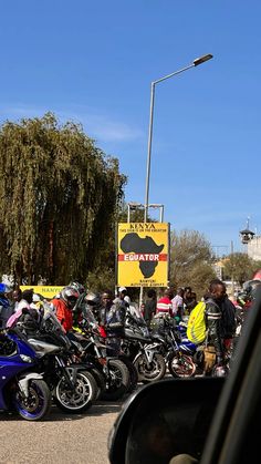 a group of motorcycles parked next to each other in a parking lot with people standing around