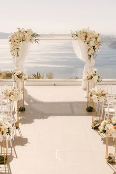 an outdoor ceremony setup with white flowers and greenery