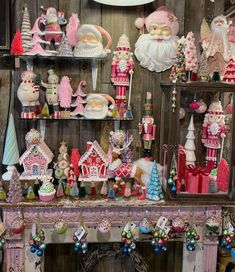 christmas decorations and ornaments are on display in a room with wood paneled walls, including santa's workshop