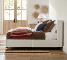 a white bed sitting in a bedroom next to a wooden floor