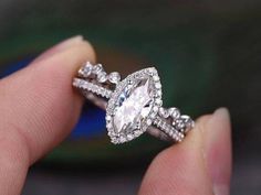 a woman's hand holding an engagement ring with two rows of diamonds on it