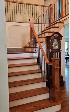 a grandfather clock sitting on top of a wooden stair case next to a banister