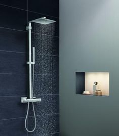 a shower head with thermostaer and hand held shower faucet in front of it