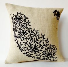 an embroidered pillow with black leaves on it