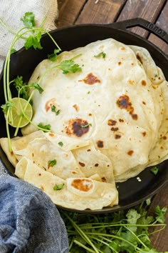 tortillas in a cast iron skillet with cilantro and lime