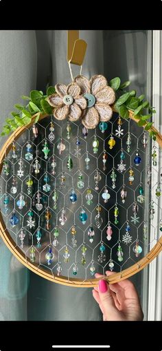 a person holding up a tray with beads and flowers on it in front of a window