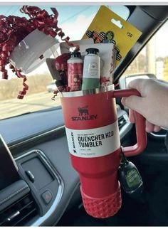 someone is holding up a cup filled with alcohol and other items in their car's dashboard