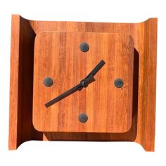 a square wooden clock with black hands on a white background is seen in this image