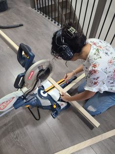 a woman using a circular saw to cut planks on the floor in her home