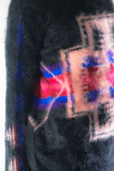 a woman wearing a black sweater with red, white and blue designs on the back