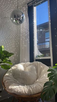 a white chair sitting in front of a window next to a potted plant