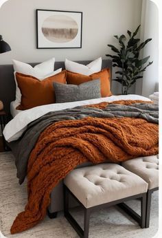 a bed with orange and grey blankets on it