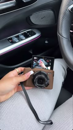 a person holding a camera in their hand while sitting in a car with the door open