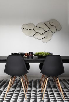 a dining table with four chairs and plates on it in front of an abstract mirror