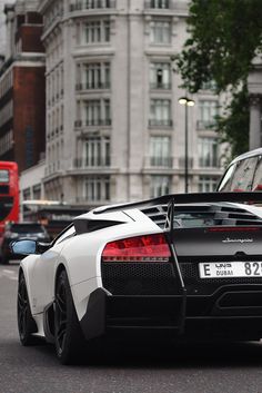 a black and white sports car parked on the side of the road next to a red double decker bus