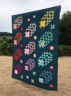 a blue quilt with stars on it sitting in the sand