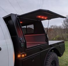 the back end of a black truck with its lights on and it's bed open