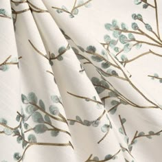 a close up view of a white fabric with blue flowers and leaves on the side