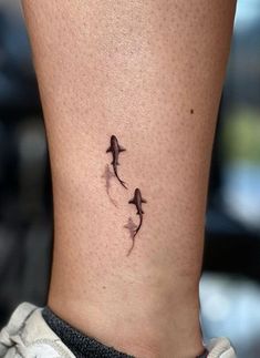 a small tattoo on the ankle of a woman's lower leg, with three birds flying