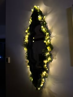 a mirror that has lights on it in the shape of a tree with leaves around it