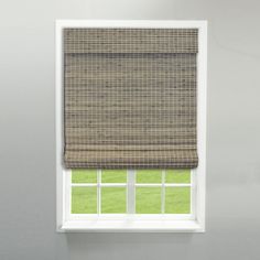 a window with a brown roman blind in front of it and green grass outside the window