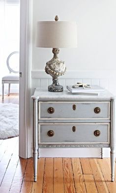 a white dresser with drawers and a lamp on top