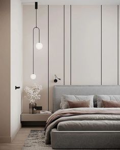 a bedroom with white walls and grey bedding, two lamps hanging above the bed