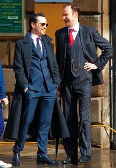 two men in suits standing next to each other