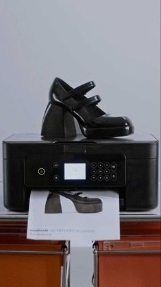 a pair of black shoes sitting on top of a printer