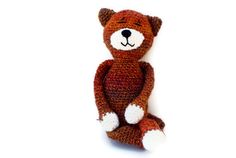 a crocheted teddy bear sitting on the floor with its legs crossed and eyes closed