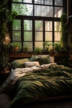 an unmade bed with green sheets and pillows in front of a large window filled with potted plants