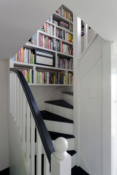 the stairs are lined with books and there is also a book shelf on one side