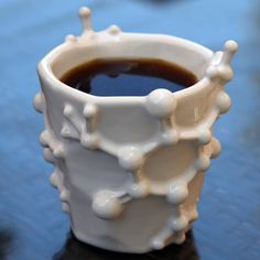 a white coffee cup filled with liquid on top of a blue table next to other items