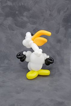 the balloon dog is wearing an orange and white hat with black ears, yellow feet and tail