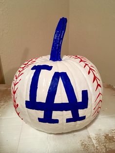 a painted baseball pumpkin with the word la on it's side, sitting on a table