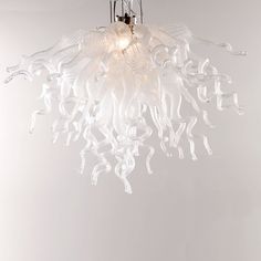 a glass chandelier hanging from the ceiling in a room with white walls and flooring