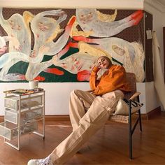 a man sitting on a chair in front of a painting