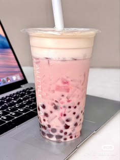 a drink sitting on top of a laptop computer next to a cup with a straw in it