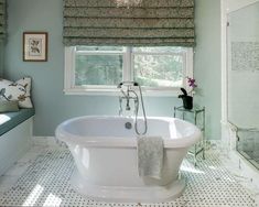 a white bath tub sitting under a window in a bathroom