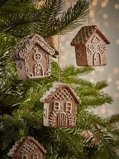 three ornaments hanging from a christmas tree with lights in the background