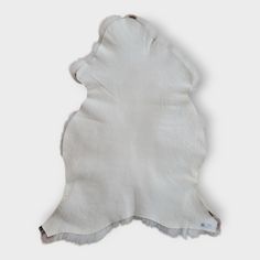 a white sheepskin rug is laying on the floor with its back facing away from the camera