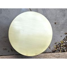 a round metal object sitting on top of a cement wall next to gravel and rocks