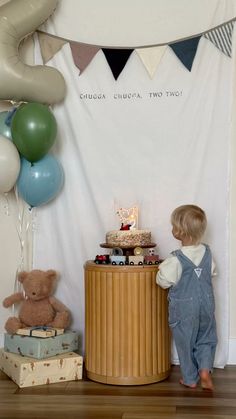 a small child standing in front of a table with cake and teddy bears on it